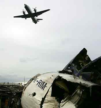 An aircraft flies over the wreckage of the plane which crashed into a residential area in Medan September 6, 2005.