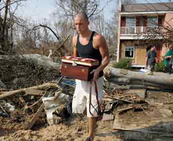 David Brown carries belongings from a home in Bay Saint Louis, Mississippi, September 5, 2005. Thousands of families returned to pick up pieces of their battered homes outside New Orleans on Monday and President George W. Bush promised to fix bungled rescue efforts after Hurricane Katrina killed as many as 10,000 people.