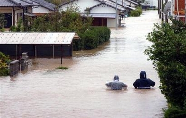 People wade through a flooded road in a residential quarter of Miyazaki city, southern Japan, Tuesday, Sept 6, 2005.