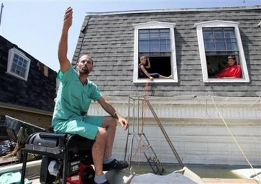 Dennis Rizzuto, 38, gestures to his home and belongings as he sits outside his Chalmette, La., home Tuesday, Sept. 6 2005.