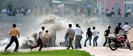 Chinese tourists watch the tide on the bank of Qiantang River in Hangzhou September 7, 2005. Tides waves are seen each year during the eighth month of the lunar calendar, with the most violent tide reaching a height of nine metres.