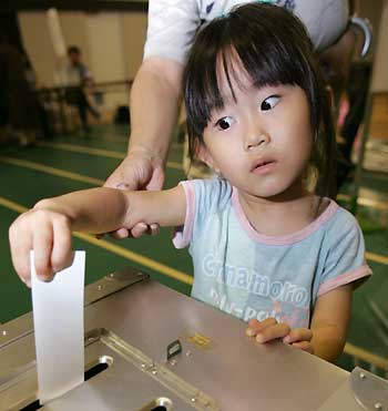 A Japanese girl slips her grandmother's vote into a ballot box at a polling station in Tokyo for Japan's general election September 11, 2005. [Reuters]