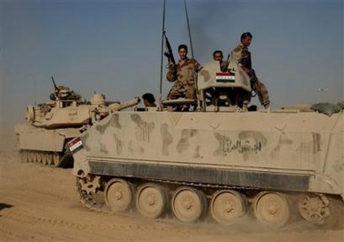 Iraqi soldiers ride on top of an armored vehicle next to a U.S. tank, as they participate in an operation in Tal Afar, northwestern Iraq, Monday, Sept. 12, 2005.[AP]