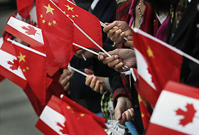 People gather at the airport holding Chinese and Canadian flags while waiting for the arrival of Chinese President Hu Jintao in Vancouver, British Columbia, September 16, 2005. 
