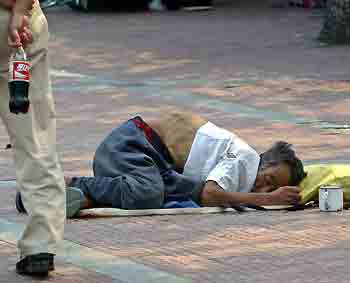 A Chinese man walks past a beggar sleeping on the street in Beijing. [Reuters/file]