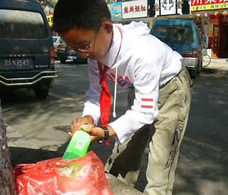 Sun collects plastic bottles on a street after school.