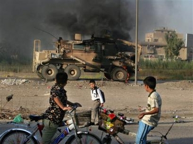 An Iraqi boy walks to school passing by a burning US military vehicle, in Baghdad, Iraq, Thursday, Sept. 29, 2005. 