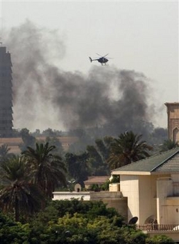 A US helicopter hovers as a plume of black smoke rises from the edge of the Green Zone, the heavily guarded area where foreign embassies and Iraq's parliament are based, in Baghdad, Iraq, Tuesday, Oct. 4 2005, following an explosion.