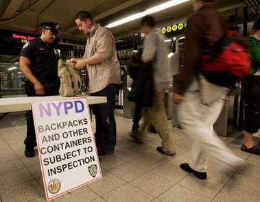 A New York City police officer searches the bag of a subway passenger in New York City October 6, 2005. A news conference was called earlier in the evening to address a terrorist threat involving the New York City subways.