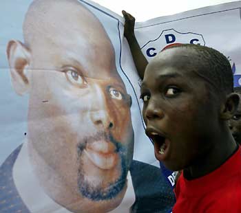 A man shouts while standing in front of a poster of Liberian presidential hopeful George Weah during a rally in Monrovia, Liberia October 8, 2005. Tens of thousands of supporters of Weah brought Monrovia to a standstill on Saturday as the millionaire soccer star held a final campaign rally before Liberia's first post-war elections. 