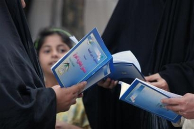 An Iraqi child looks on as women hold copies of the country's draft constitution in Baghdad, Iraq, Sunday, Oct. 9 2005.