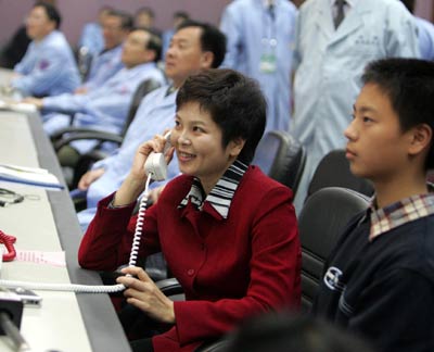 Wang Jie talks with her husband astronaut Fei Junlong through a phone at the Beijing Aerospace Command and Control Center Wednesday October 12, 2005. Fei and Nie Haisheng are orbiting the Earth in China's second manned spacecraft Shenzhou VI which was launched Wednesday morning. [Xinhua]
