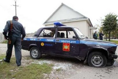 A Russian policeman walks past a damaged police car in Nalchik, Russia October 13, 2005.