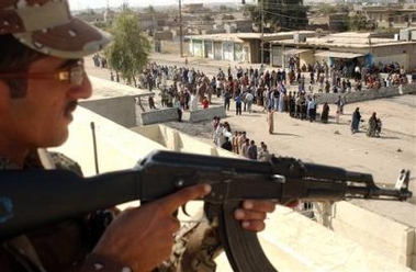 A soldier stands guard on a rooftop as Iraqis wait in long lines to vote in Iraq's referendum on the new constitution in Mosul, Iraq, Saturday Oct. 15 2005.