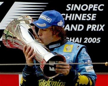 Renault's World Champion Formula One driver Fernando Alonso of Spain kisses the trophy on the podium after winning the Chinese Grand Prix in Shanghai October 16, 2005.