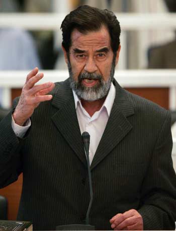 Saddam Hussein defiantly speaks to the Presiding Judge Rizgur Ameen Hana Al-Saedi as his trial begins in a heavily fortified courthouse in Baghdad's Green Zone October 19, 2005. Nearly two years after he was found in hiding, former Iraqi president Saddam Hussein goes on trial Wednesday charged with crimes against humanity for the death of more than 140 Shi'ite Muslim men over two decades ago. 