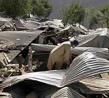 A Kashmiri earthquake survivor tries to salvage belongings from a destroyed house in Muzaffarabad, capital of Pakistani-administered Kashmir October 22, 2005. [Reuters]