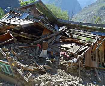 Kashmiri earthquake survivors look for belongings from the rubble of their house at the Line of Control (LoC) in Teetwal, 195 km (122 miles) north of Srinagar October 22, 2005. The engineering battalion promised by NATO to help reach untold numbers of quake survivors in the rugged hills of northern Pakistan cannot arrive soon enough, an international aid official said on Saturday. [Reuters]