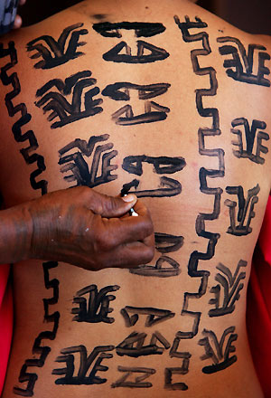 Miss Traditional contestant Shirley O'Connor from the Central Highlands Province waits as her body was being painted with traditional designs by a relative before performing in the contest held in the Papua New Guinea capital city of Port Moresby October 29, 2005. The competition, which raised funds for a local charity, involves contestants wearing their Province's traditional attire, including tattoo designs, and a performance involving dancing and singing which concludes with a speech explaining these traditional acts.