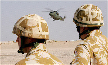 British soldiers watch as a helicopter lands just outside Basra in October 2005.