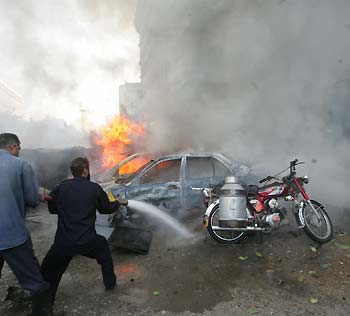 Pakistani firemen try to extinguish cars set ablaze after a bomb blast in Karachi November 15, 2005. A car bomb killed at least six people on Tuesday in the southern Pakistani city, according to an ambulance crew at the scene. Police said the car had been parked outside a KFL fast food outlet, and caused casualties in a nearby office block housing several oil and gas companies.