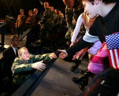 President Bush, left, reaches out to shake hands with Mikey Garrett, 9, whose father is Col. Michael X. Garrett of the Army 4th Brigade Combat Team, after Bush spoke to troops and their families about the war on terror during a stop at Elmendorf Air Force Base in Anchorage, Alaska, Monday, Nov. 14, 2005. [AP]