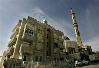 A mosque minaret is seen next to an apartment building used as a safe house where police arrested the would-be bomber Sajida Al-Rishawi Sunday in the city of Amman, Jordan, Tuesday, Nov. 15, 2005.