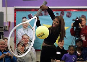 Serena Williams uses a giant tennis racket to swing at a huge tennis ball duirng a demonstration at Seattle's T.T. Minor Elementary School as she visited with her sister, Venus Williams, Thursday, Nov. 17, 2005.