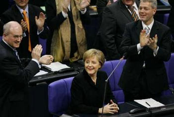 Christian Democrat (CDU) leader and German Chancellor-elect Angela Merkel (C) receives applause after being elected during a parliamentary meeting in Berlin November 22, 2005. Merkel was elected Germany's first woman chancellor on Tuesday in a parliamentary vote that ends months of political uncertainty and puts her atop a fragile coalition that must prove it can revive the economy. At left is CDU party member Volker Kauder and at right is CDU party member Norbert Roettgen. [Reuters]