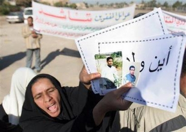A woman shouts as she holds the pictures of her sons and a poster reading: Where are my sons?, during a protest in front of Iraq's Human Rights Ministry, in Baghdad, Iraq, Sunday, Nov. 27, 2005.