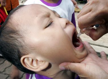 An Indonesian health official vaccinates a child during mass polio immunisation in Jakarta November 30, 2005.
