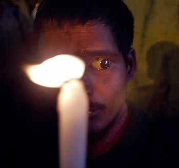 A half blind man holds a candle as he walks along with commercial sex workers during an AIDS awareness rally in Mumbai, India November 29, 2005. The rally ended with sex workers making a pledge to protect themselves from getting AIDS and also to help in the treatment and respect people who are suffering from AIDS. 