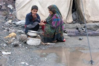 Kashmiri earthquake survivors prepare food outside their tent after rain in Muzaffarabad, capital of Pakistani Kashmir, Tuesday, Nov. 29, 2005.