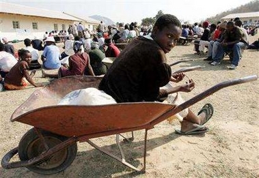 A woman sits on her wheelbarrow while waiting for food aid southeast of the Zimbabwe capital of Harare, August 12, 2005.