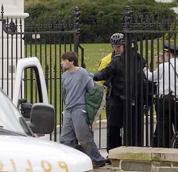 A man identified as Shawn A. Cox, 29, of Arkansas is led away by U.S. Secret Service agents after climbing over the fence at the White House in Washington December 4, 2005. President George W. Bush and First Lady Laura Bush were both in the White House at the time. [Reuters]