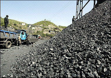Coal is loaded onto delivery trucks from a mine. 