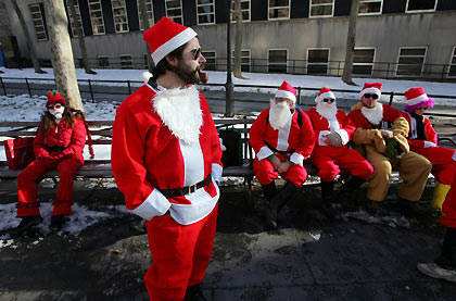 Santas wait for more Santas to gather in Brooklyn, New York December 10, 2005. They were participating in the annual New York SantaCon, which involves hundreds of people in cheap Santa suits walking around the city, singing naughty carols, drinking, and generally spreading holiday cheer and mayhem. 
