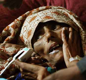 A Kashmiri earthquake survivor lies in a hospital in Muzaffarabad in Pakistan-administered Kashmir December 12, 2005. The woman was rescued from the rubble after more than two months in Kamsar Camp near Muzaffarabad on Monday, local media reported. [Reuters]