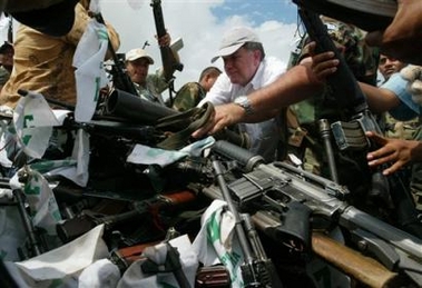 Colombian Peace Commissioner Luis Carlos Restrepo, center, helps collect weapons into a pile during a ceremony in Otu, in northwest Colombia, Monday, Dec. 12, 2005.