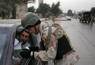 A soldier checks the identification card of an Iraqi driver at a checkpoint in Baghdad, Iraq, Tuesday Dec. 13, 2005. 