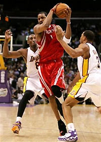 Houston Rockets' Tracy McGrady, center, tries to jump through the defense of Los Angeles Lakers' Kobe Bryant, left, and Devean George, right, during the second quarter of NBA basketball action, Sunday, Dec. 18, 2005, in Los Angeles. 