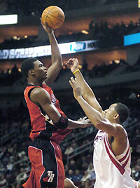 Raptors' Chris Bosh (L) takes a one hand jump shot over Houston Rockets' Juwan Howard in the first quarter of their NBA game in Houston, December 21, 2005.