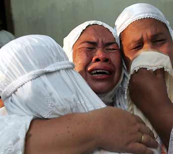 Alfiyati (C), an Acehnese woman who lost one of her children in the Indian Ocean tsunami, cries after praying at a memorial service for the tsunami victims in Landung, Banda Aceh, December 25, 2005. Construction spending in Aceh, devastated by last year's tsunami, will soon reach $2 billion a year, the United Nations Development Programme said. A 9.15 magnitude earthquake triggered the tsunami which left 170,000 people dead or missing in Aceh alone.