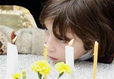 A girl rests her head during a public memorial for the victims of last years Beslan school siege in the town's cemetery, September 3, 2005.