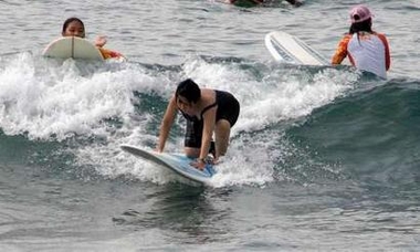 Philippine President Gloria Macapagal Arroyo (C) rides a wave at a surfing camp in San Juan town, La Union province, northern Philippines December 27, 2005. 