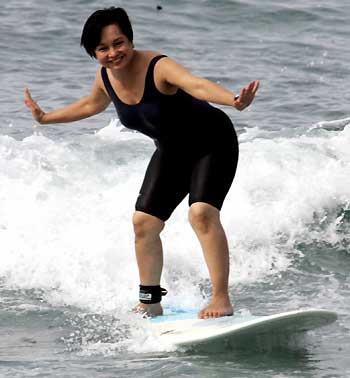 Philippine President Gloria Macapagal Arroyo rides a wave at a surfing camp in San Juan town, La Union province, northern Philippines December 27, 2005. Arroyo is currently spending the holidays in northern Philippines with her family.