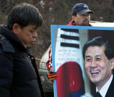 A South Korean man supporting stem-cell scientist Hwang Woo-suk holds a portrait of Hwang in front of Seoul National University in Seoul December 29, 2005.