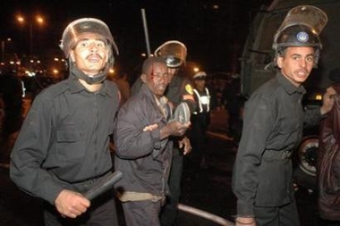 Egyptian riot police arrest an injured Sudanese man in a Cairo public square December 30, 2005. 