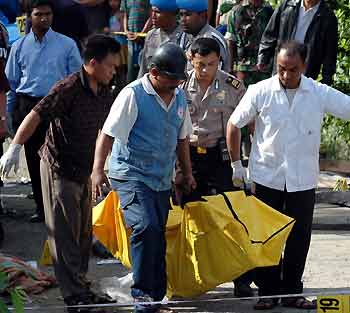 Indonesian police and paramedics removed a body after a blast at a market in the town of Palu, the capital of volatile Indonesia's Central Sulawesi province, December 31, 2005. A suspected bomb blast rocked a crowded market selling pork in eastern Indonesia on Saturday, killing six people and wounding 45, local media reported. 