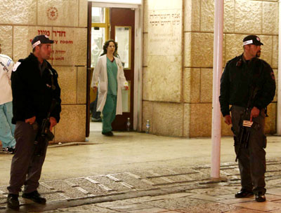 Israeli police officers stand guard in front of the entrance to the emergency room at the Hadassah Ein Karem hospital, where Israeli Prime Minister Ariel Sharon is hospitalised in Jerusalem early January 5, 2006. Sharon was taken for surgery on Wednesday after suffering a cerebral haemorrhage, the director of Jerusalem's Hadassah Hospital said. 
